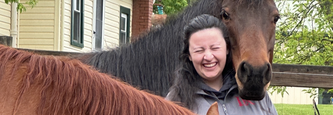 Horse rests their head on a students shoulder 