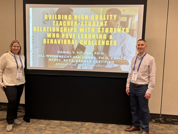 Dr. Van Horne and Daniel posing in front of a yellow powerpoint screen.